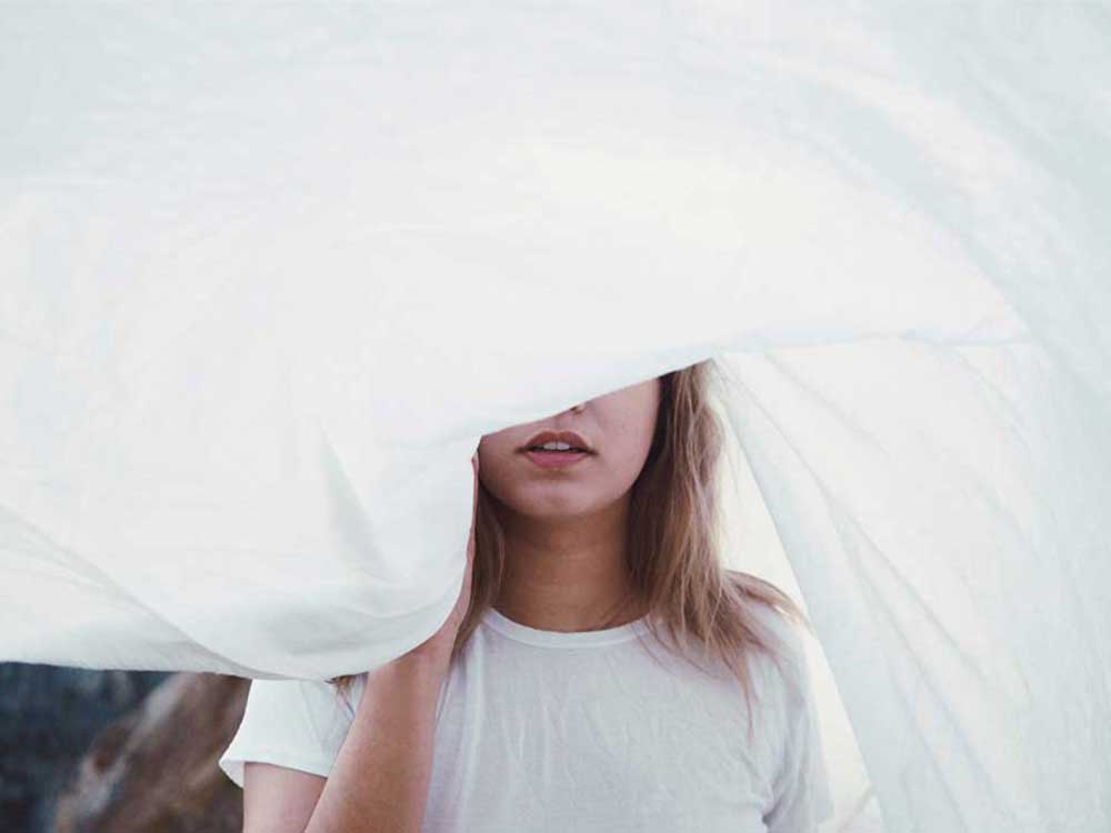 Girl with face covered by sheet